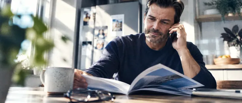 Person reading a vision benefits booklet while calling their insurer